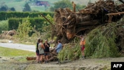 Orang-orang berdiri di samping puing-puing di daerah yang terkena banjir setelah Topan Gabrielle dekat Napier, Selandia Baru, 16 Februari 2023. (AFP)