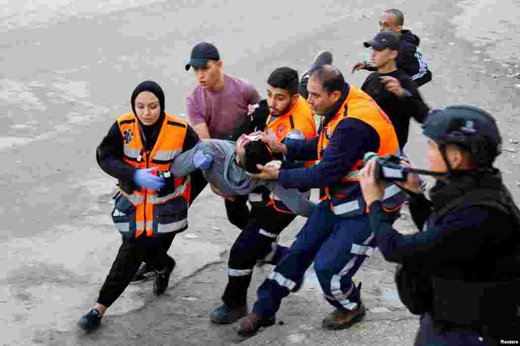 Medics carry an injured person during an Israeli military raid in Jenin, in the Israeli-occupied West Bank, amid the ongoing conflict between Israel and Hamas.
