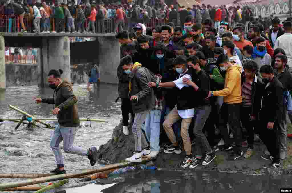 People try to cross the Bagmati River to avoid the crowded bridge at the premises of Pashupatinath Temple during the Shivaratri festival in Kathmandu, Nepal, Feb. 18, 2023. 