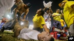 Rescatistas atienden a un aficionado herido tirado en la cancha del estadio Cuscatlán en San Salvador, El Salvador, el 20 de mayo de 2023.