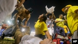 Tim penyelamat merawat seorang penggemar yang cedera tergeletak di lapangan stadion Cuscatlan di San Salvador, El Salvador, 20 Mei 2023. (Foto: AP)