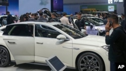 FILE - Visitors look at cars at the BYD booth during the China Auto Show in Beijing, China, April 26, 2024. The EU threatened on June 12, 2024, to increase tariffs on Chinese electric vehicles, escalating a trade dispute over Beijing's subsidies for the exports.