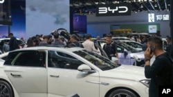 Para pengunjung melihat mobil-mobil yang terpajang di stan BYD dalalam pameran otomotif di Beijing, China, pada 26 April 2024. (Foto: AP/Tatan Syuflana)