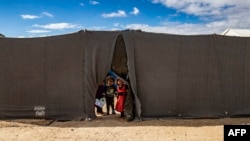 FILE - Children peek through the opening of a tent at the Kurdish-run al-Hol camp which holds suspected relatives of Islamic State (IS) group fighters, in the northeastern Syrian Hasakeh governorate, on Feb. 17, 2021.