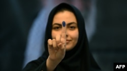 Seorang perempuan Iran memperlihatkan jarinya yang sudah ditandai tinta usai mencoblos untuk memilih presiden baru, di Kedubes Iran di Kuwait, Jumat, 28 Juni 2024. (Foto: Yasser Al-Zayyat/AFP)