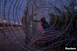 Eliana, 22, a migrant from Venezuela, holds her 3-year-old daughter, Chrismarlees, as she shouts toward an Army National Guard soldier in El Paso, Texas, March 26, 2024.