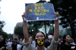 A member of an environmental civic group holds a sign during a rally to demand the withdrawal of the Japanese government's decision to release treated radioactive water into the sea from the damaged Fukushima nuclear power plant, in Seoul, South Korea, Tuesday, Aug. 22, 2023. (AP Photo/Lee Jin-man)