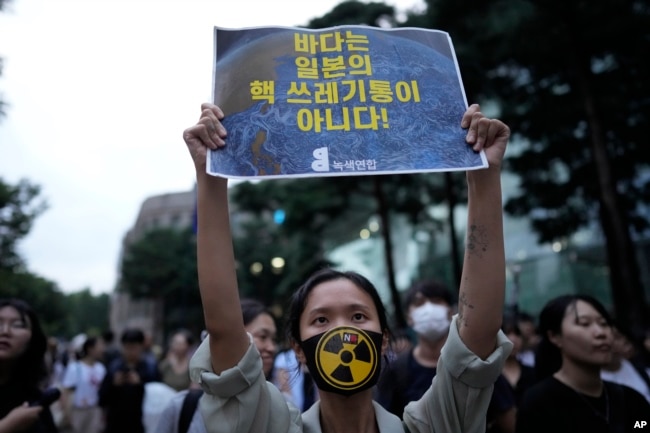 A member of an environmental civic group holds a sign during a rally to demand the withdrawal of the Japanese government's decision to release treated radioactive water into the sea from the damaged Fukushima nuclear power plant, in Seoul, South Korea, Tuesday, Aug. 22, 2023. (AP Photo/Lee Jin-man)