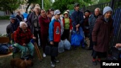Vovchansk area residents, who fled their homes due to Russian military strikes, gather at an evacuation point at an unidentified location in Ukraine's Kharkiv region, May 14, 2024. 