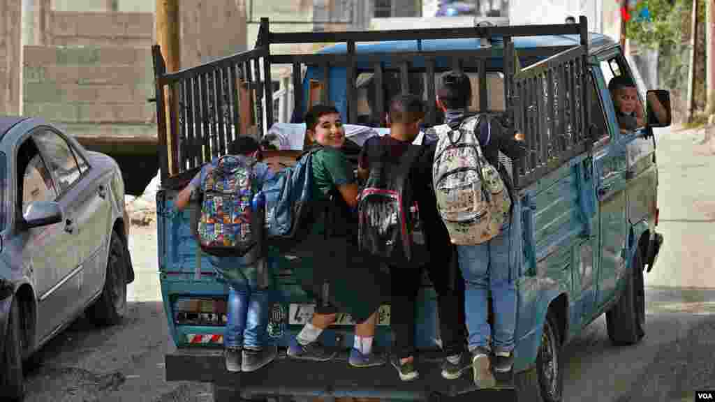 Varios niños regresan de la escuela colgados de una vieja furgoneta en el campo de refugiados palestinos de Nur Shams, en Tulkarem, Cisjordania.