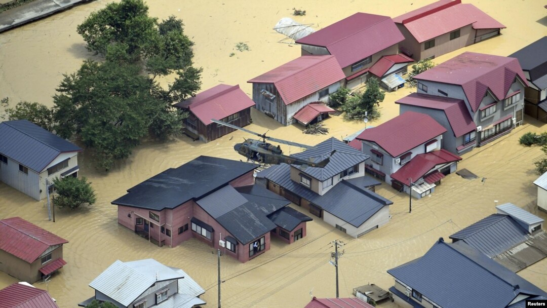 An aerial view shows a Japan Self-Defense Forces helicopter conducting a search and rescue operation over a flooded residential area in Tozawa Town, Yamagata Prefecture, Japan, July 26, 2024, in this photo taken by Kyodo.