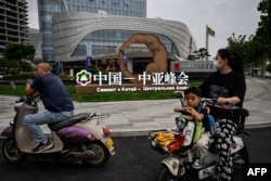 中國西安市民路過街頭豎立的中亞峰會宣傳牌。（2023年5月17日）