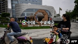 中国西安市民路过街头竖立的中亚峰会宣传牌。（法新社2023年5月17日）