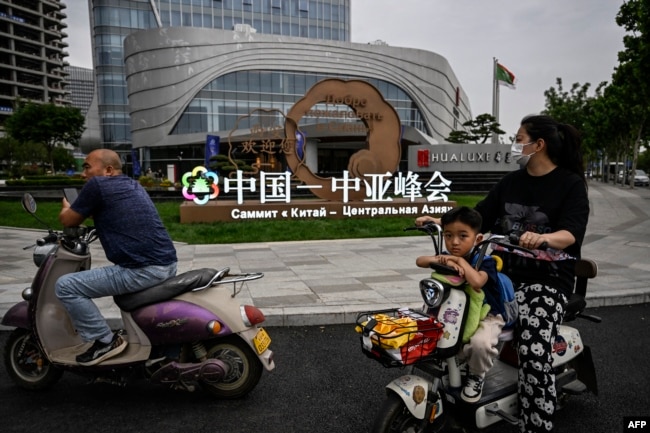 中国西安市民路过街头竖立的中亚峰会宣传牌。(2023年5月17日)