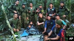 In this photo released by Colombia's Armed Forces Press Office, soldiers and Indigenous men pose for a photo with the four Indigenous brothers who were missing after a deadly plane crash, in the Solano jungle, Caqueta state, Colombia, June 9, 2023. 