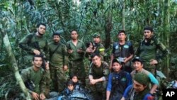 In this photo released by Colombia's Armed Forces Press Office, soldiers and Indigenous men pose for a photo with the four Indigenous brothers who were missing after a deadly plane crash, in the Solano jungle, Caqueta state, Colombia, June 9, 2023. 