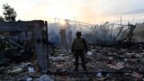 A police expert looks at damage to an industrial area in the Ukrainian capital of Kyiv, after a massive overnight missile attack on Sept. 21, 2023.