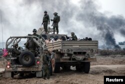 Tahanan Palestina duduk di dalam truk saat tentara Israel berjaga di tengah konflik yang sedang berlangsung antara Israel dan Hamas, di Jalur Gaza, 8 Desember 2023. (Foto: REUTERS/Moti Milrod)