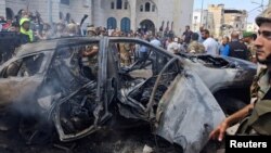 People and Lebanese army members stand near a burned car after an Israeli strike on the outskirts of the southern port city of Sidon, according to two Palestinian sources, in Lebanon, Aug. 21, 2024. 