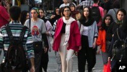 Iranian women, some not wearing their mandatory Islamic headscarves, walk in downtown Tehran, Iran, Sept. 9, 2023. 