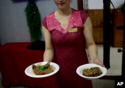 Seorang pramusaji menunjukkan hidangan yang terbuat dari daging anjing di Pyongyang House of Sweet Meat, restoran khusus daging anjing di Pyongyang, Korea Utara, Rabu, 25 Juli 2018. (AP/Dita Alangkara)