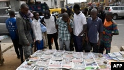 People gather around a newsstand at Ikeja district of Lagos on Monday Feb. 27, 2023 to glance through dailies as the country awaits results for the presidential elections. 