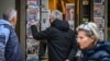 FILE - Passers-by read the front pages of newspapers hanging at a kiosk in Athens, Dec. 16, 2021. Reporters Without Borders in 2023 ranked Greece 107 in the world out of 180 countries in terms of media freedom.