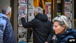 FILE - Passers-by read the front pages of newspapers hanging at a kiosk in Athens, Dec. 16, 2021. Reporters Without Borders in 2023 ranked Greece 107 in the world out of 180 countries in terms of media freedom.