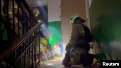 Firefighters try to cut a door to evacuate people from a building damaged by a Russian missile strike, amid Russia's attack on Ukraine, in Mykolaiv, Ukraine, in this screengrab taken from a handout video released on April 27, 2023.