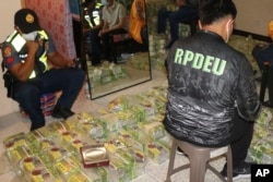 Polisi memeriksa kantong teh yang diduga mengandung sabu saat penggerebekan di sebuah rumah di kota Baguio, Filipina utara pada Rabu 29 Maret 2023. (Kanwil Polda Cordillera RPIO via AP)