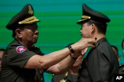 Panglima militer Kamboja Hun Manet (kanan), putra Perdana Menteri Kamboja Hun Sen, menerima promosi kenaikan pangkat jenderal bintang empat dari menterinya Tea Banh dalam upacara Angkatan Bersenjata Kerajaan Kamboja di Kementerian Pertahanan di Phnom Penh, Kamboja, Kamis, 20 April 2023. (AP/Heng Sinith)