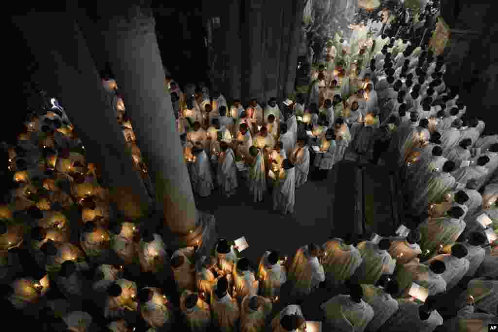 Para biarawan memegang lilin saat mereka berjalan selama prosesi Pembasuhan Kaki di Gereja Makam Suci, tempat banyak umat Kristiani percaya bahwa Yesus disalib, dikuburkan, dan bangkit dari kematian, di Kota Tua Yerusalem, Kamis, 28 Maret 2024. (Foto: Ohad Zwigenberg/AP Photo)