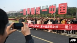 中國福建廈門豎立起一個台灣金門島可以看到的「一國兩制統一中國」的大型標語牌，旅遊者在前拍照。 （2024年1月12日）