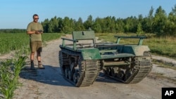 Andrii Denysenko, CEO of design and production bureau "UkrPrototyp", stands by Odyssey, an 800-kilogram (1,750-pound) ground drone prototype, at a corn field in northern Ukraine, Friday, June 28, 2024. (AP Photo/Anton Shtuka)