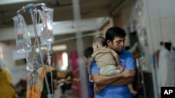 A man comforts his child suffering from dengue at Mugda Medical College and Hospital in Dhaka, Bangladesh, Sept. 14, 2023. 