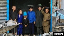 Afghan children stand at a scrap shop outside a World Food Program (WFP) distribution center in Kabul.