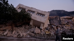 FILE - A man walks by rubble in the aftermath of an earthquake in Antakya, Turkey, on Feb. 21, 2023. Nearly a year after two earthquakes killed more than 50,000 people, Turkey began the first major trial linked to building construction that may have contributed to the deaths.