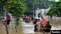 People move on rickshaws along a flooded street after a downpour in Dhaka, Bangladesh.