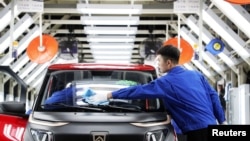 FILE - Workers are seen at the assembly line of Baojun E200 electric vehicles at a plant in Qingdao, Shandong province, China, Sept. 28, 2018. 