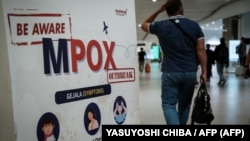 Seorang penumpang berjalan melewati spanduk yang menginformasikan tentang Cacar Monyet (MPOX) di Bandara Internasional Soekarno-Hatta di Tangerang, 26 Agustus 2024. (YASUYOSHI CHIBA / AFP)