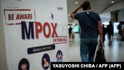 Un passager devant une bannière informant sur le Mpox à l'aéroport international Soekarno-Hatta de Tangerang, en Indonésie, 26 août 2024. AFP / Yasuyoshi Chiba