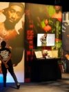 FILE - A visitor observes a display of late hip-hop artist Tupac Shakur during the press preview day for the 'Tupac Shakur. Wake Me When I'm Free' exhibition, Jan. 20, 2022, at The Canvas at L.A. Live in Los Angeles. 