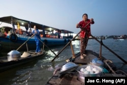 Nguyen Thi Thuy quickly rows to a passing tourist boat in the floating market of Can Tho, Vietnam, Jan. 17, 2024. (AP Photo/Jae C. Hong)