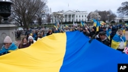 Учасники тримають український прапор під час акції біля Білого дому на підтримку України, 25 лютого 2023 р. (AP Photo/Jose Luis Magana)