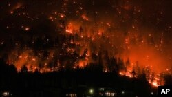 The McDougall Creek wildfire burns on the mountainside above houses in West Kelowna, British Columbia, Canada, Aug. 18, 2023. 