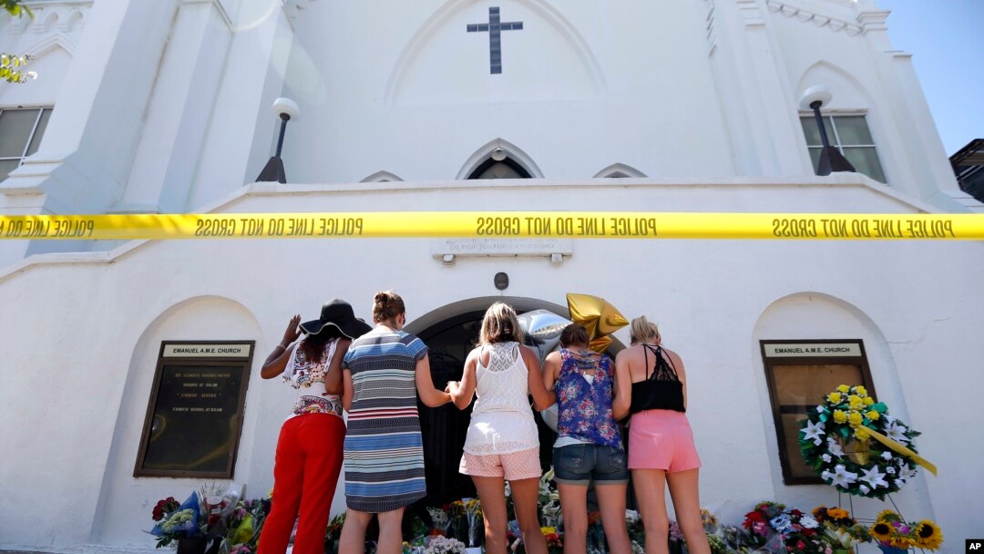 ARCHIVO - Un grupo de mujeres oran juntas en un memorial improvisado en la acera frente a la Iglesia Emanuel AME el 18 de junio de 2015 en Charleston, Carolina del Sur, EEUU.