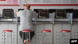 FILE - An investor looks at screens showing stock market movements at a securities company in Fuyang in China's eastern Anhui province, May 29, 2023. China halved the stamp duty on securities transactions, to take effect Monday, state media reported, Aug. 27, 2023.