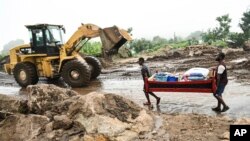 Men transport their salvaged belongings in Chiradzulu, southern Malawi, Friday March 17, 2023. 