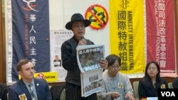 香港流亡艺术家黄国才现场拿出2021年停刊前的最后一期香港《苹果日报》，演示如何轻易违反23条立法。（美国之音 李贤）