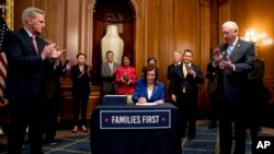 FILE - House Speaker Nancy Pelosi of Calif., with other bipartisan legislators signs the Coronavirus Aid, Relief, and Economic Security (CARES) Act, March 27, 2020, Capitol Hill.